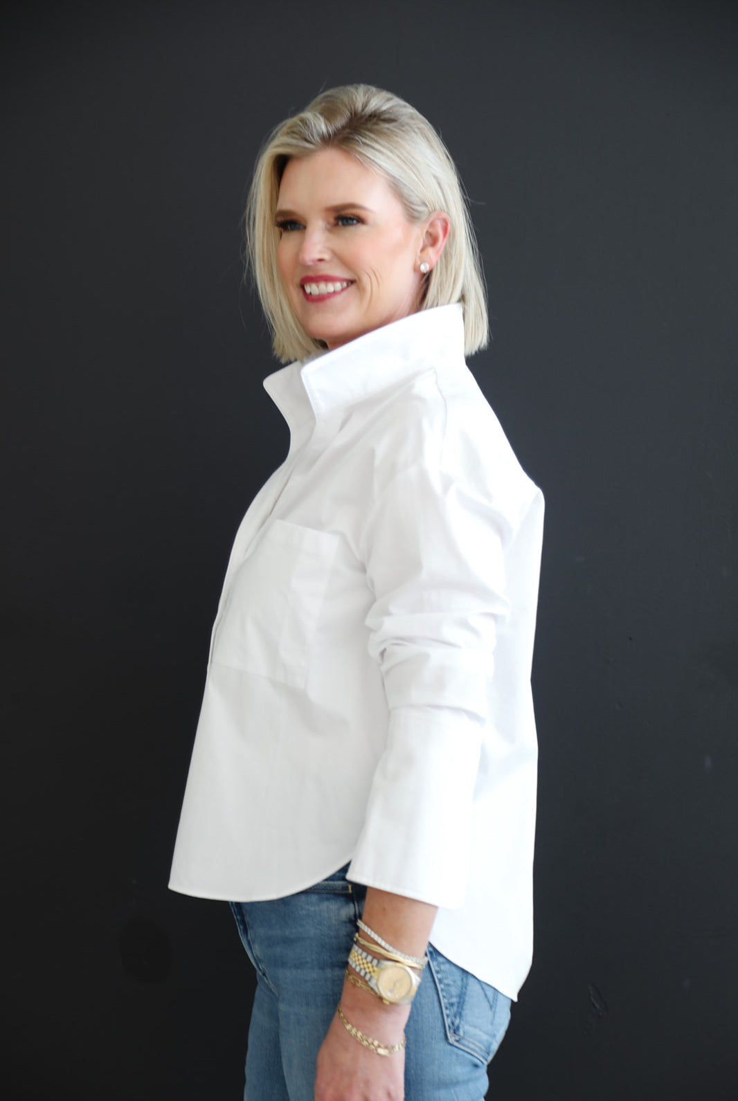 Woman wearing a white shirt and blue jeans against a black background