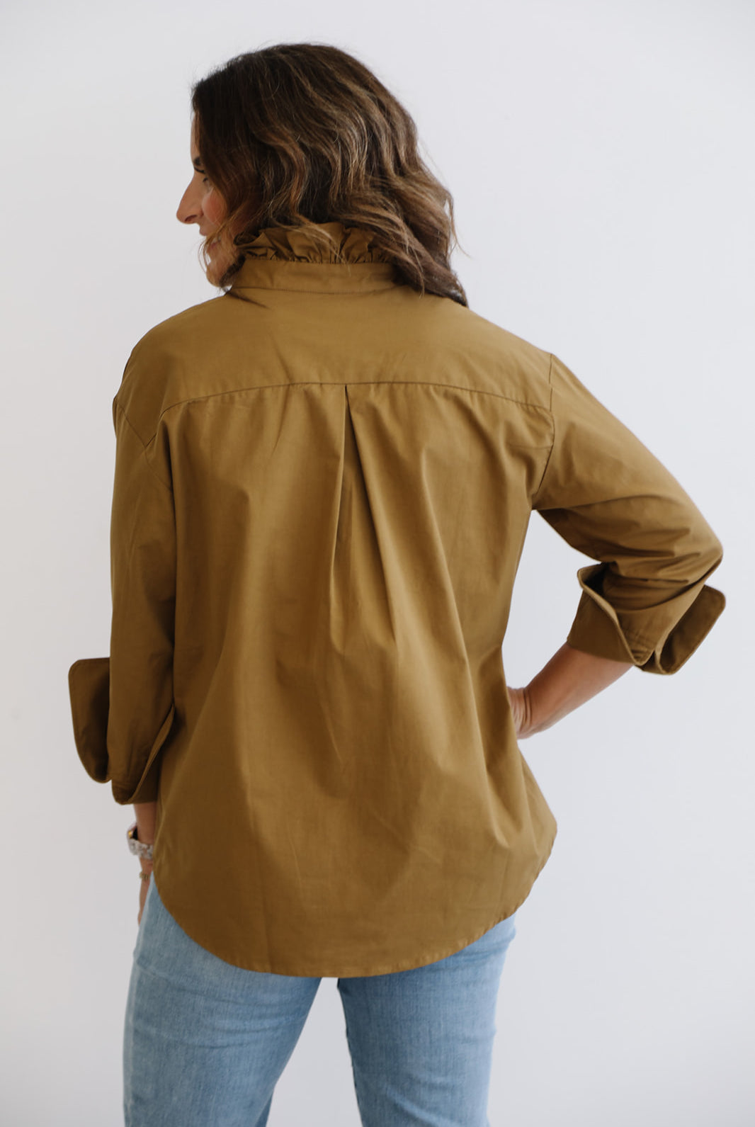 Person wearing a brown shirt and blue jeans on a white background