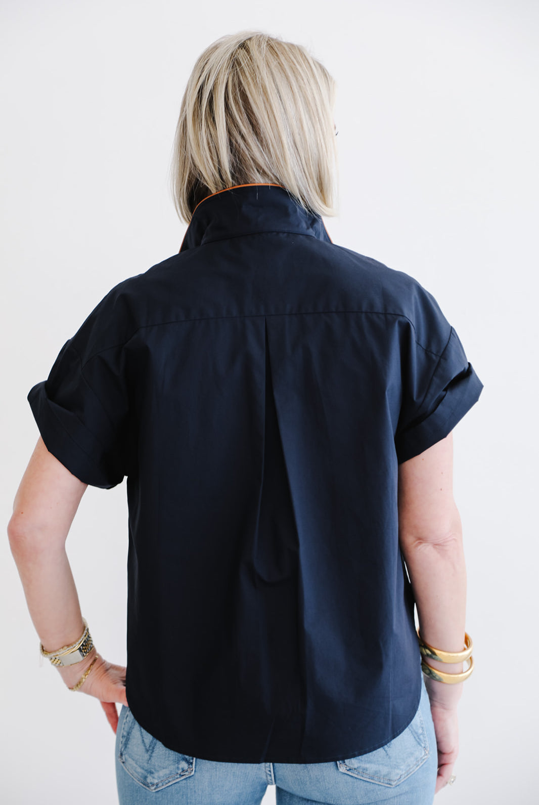 Person wearing a navy blue shirt with short sleeves on a white background