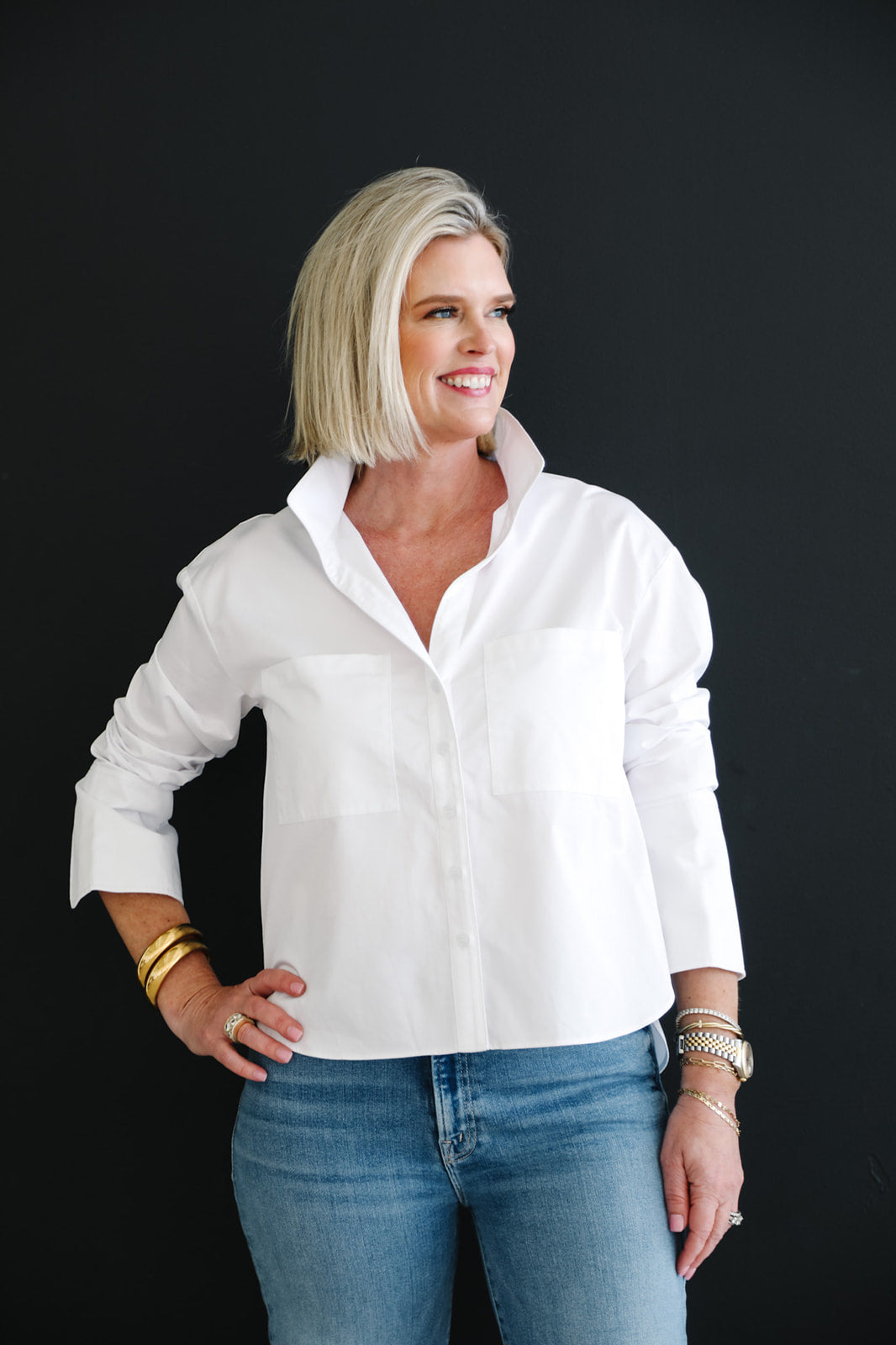 Woman wearing a white shirt and blue jeans against a black background