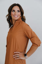 Woman wearing a brown dress with a plain background