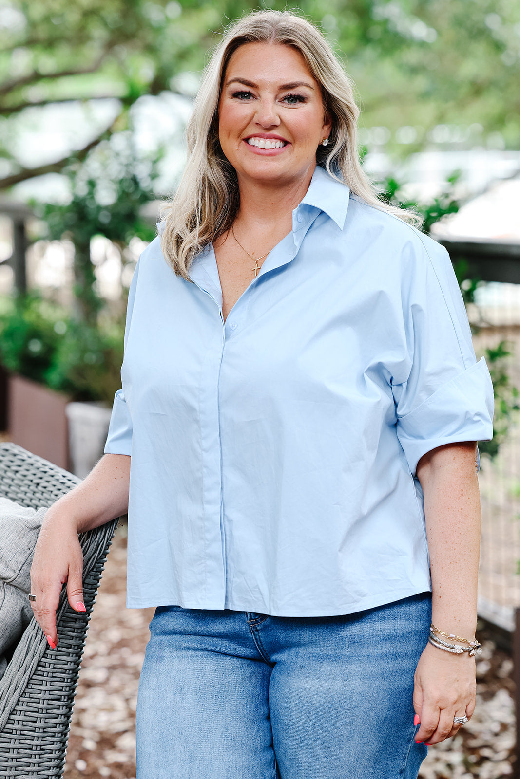 Woman wearing a light blue shirt and jeans outdoors