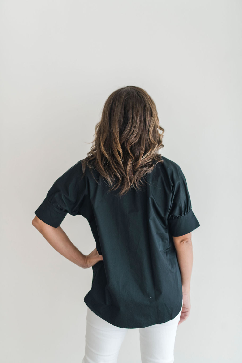 Crisp black button down shirt with a popped ruffle collar and short sleeves.