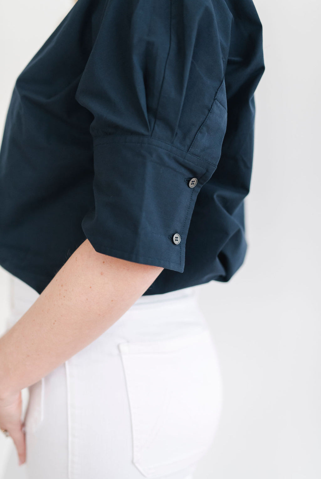 Navy blue cotton pullover style shirt with a stand up collar, a longer short sleeve with button details.
