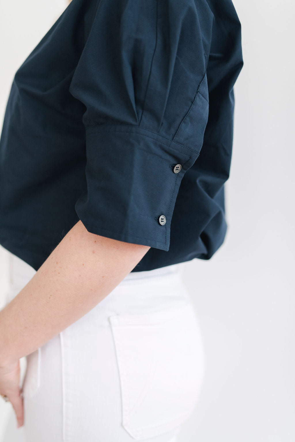 Navy blue cotton pullover style shirt with a stand up collar, a longer short sleeve with button details.