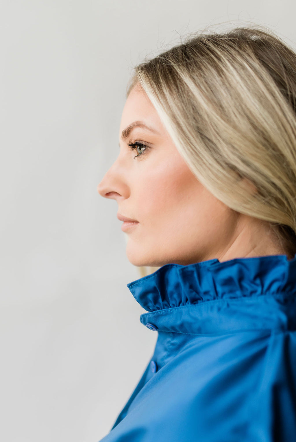 Crisp women's short sleeve button down shirt with a ruffle collar in bright blue.