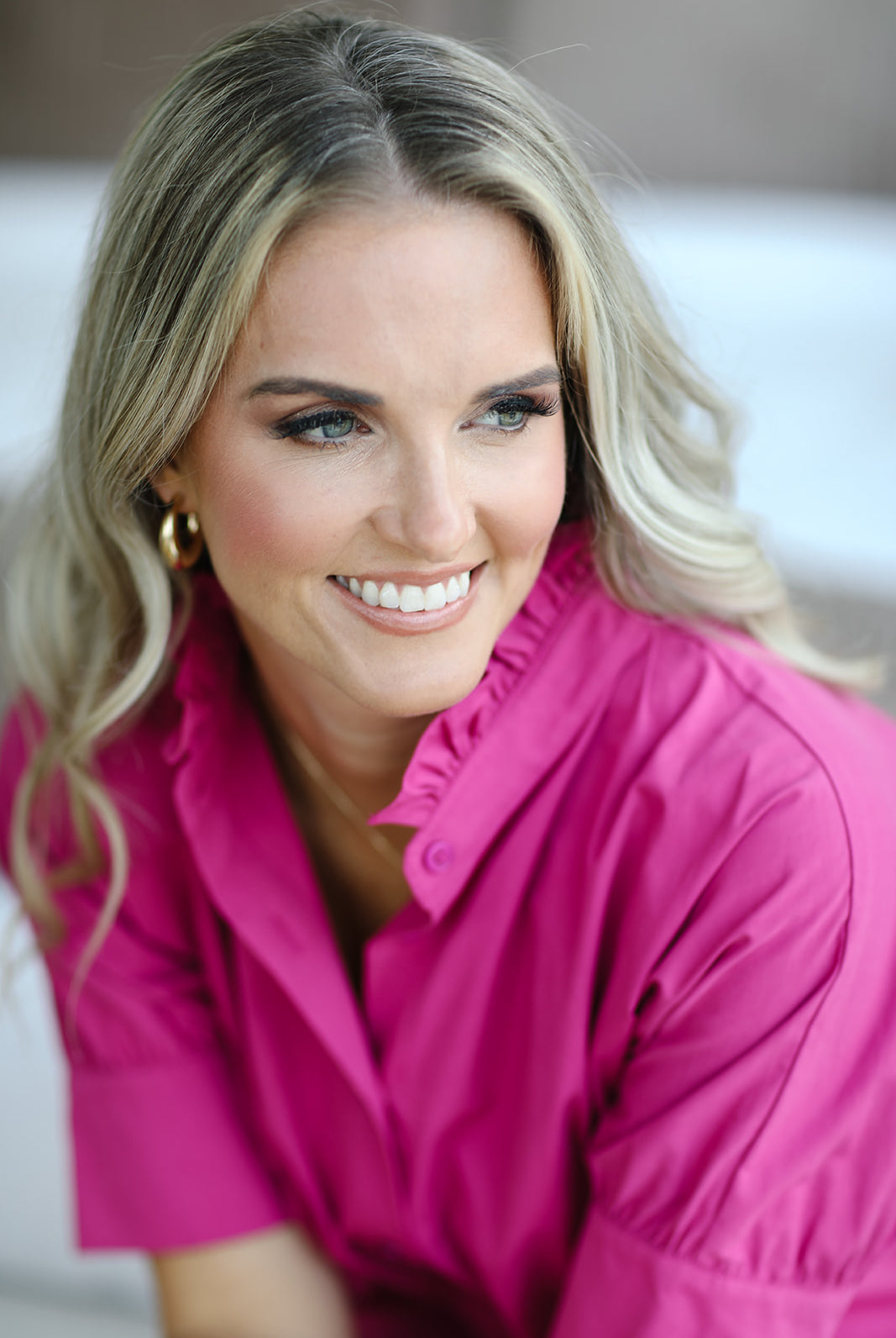 Woman wearing a bright pink shirt with a blurred background