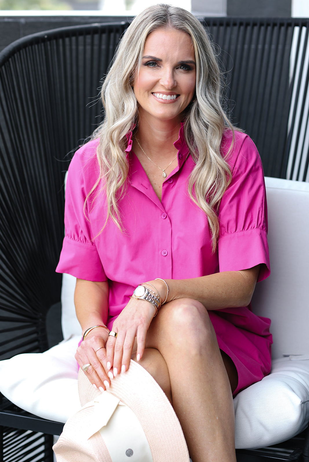 Woman in a pink shirt dress sitting on a chair outdoors