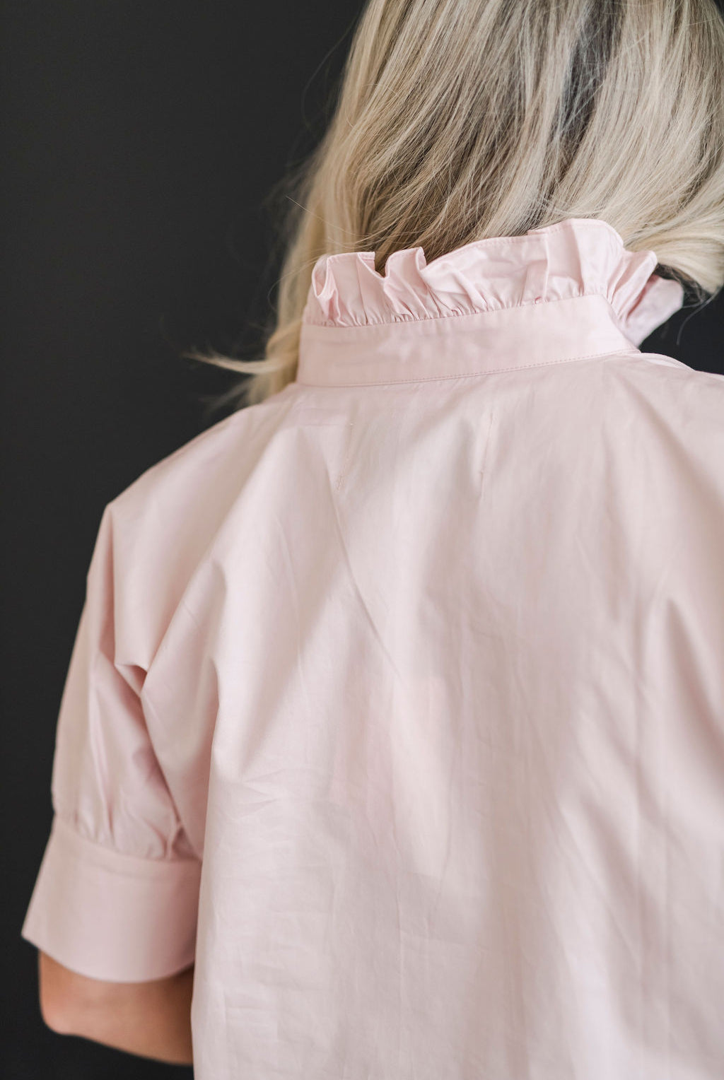 A crisp and classic shirt in a blush pink color with a ruffle collar.