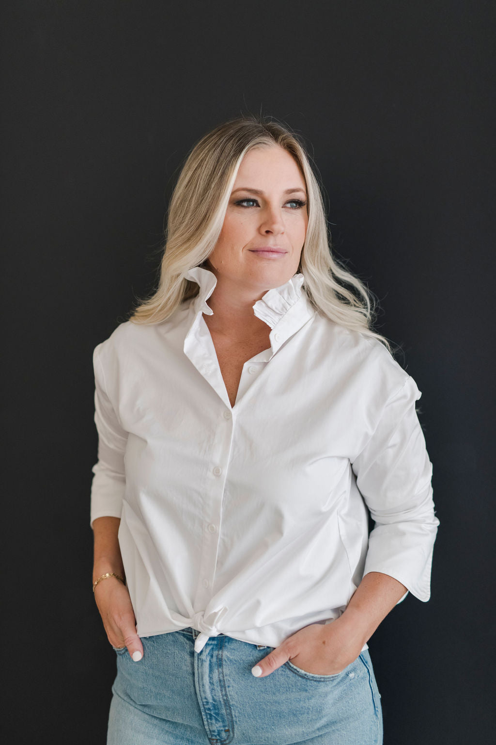 A white long sleeve button up shirt with a stand up ruffle collar and oversized cuffs.  Tied in a knot for a more casual look.