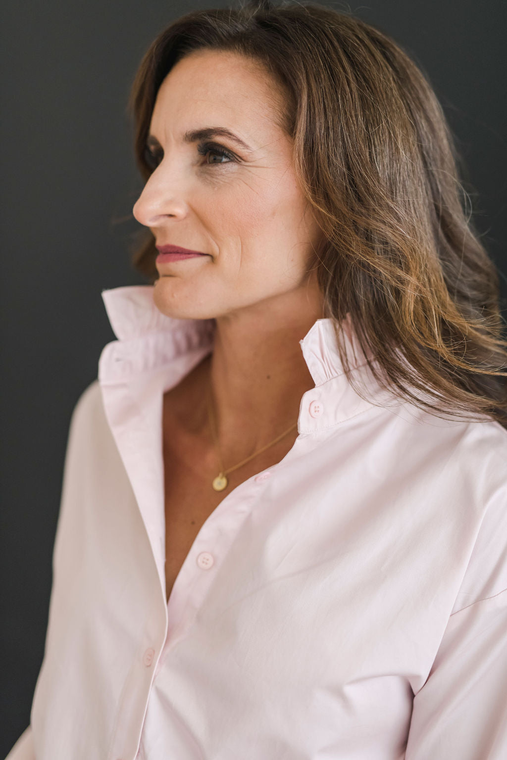 A button down shirt with a stand up ruffle collar in a beautiful blush color.  Has long sleeves and an oversized cuff.