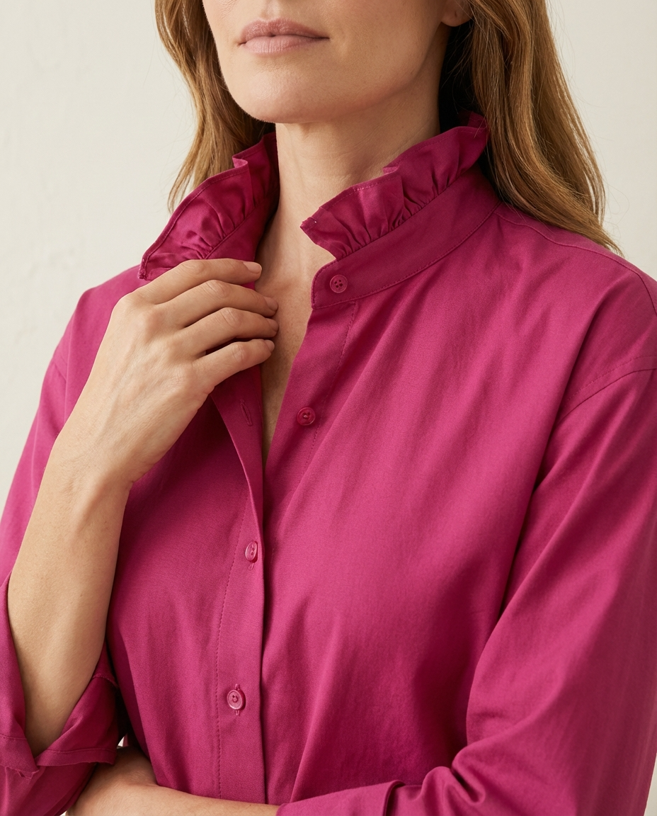Close-up of a person wearing a bright pink shirt with a neutral background