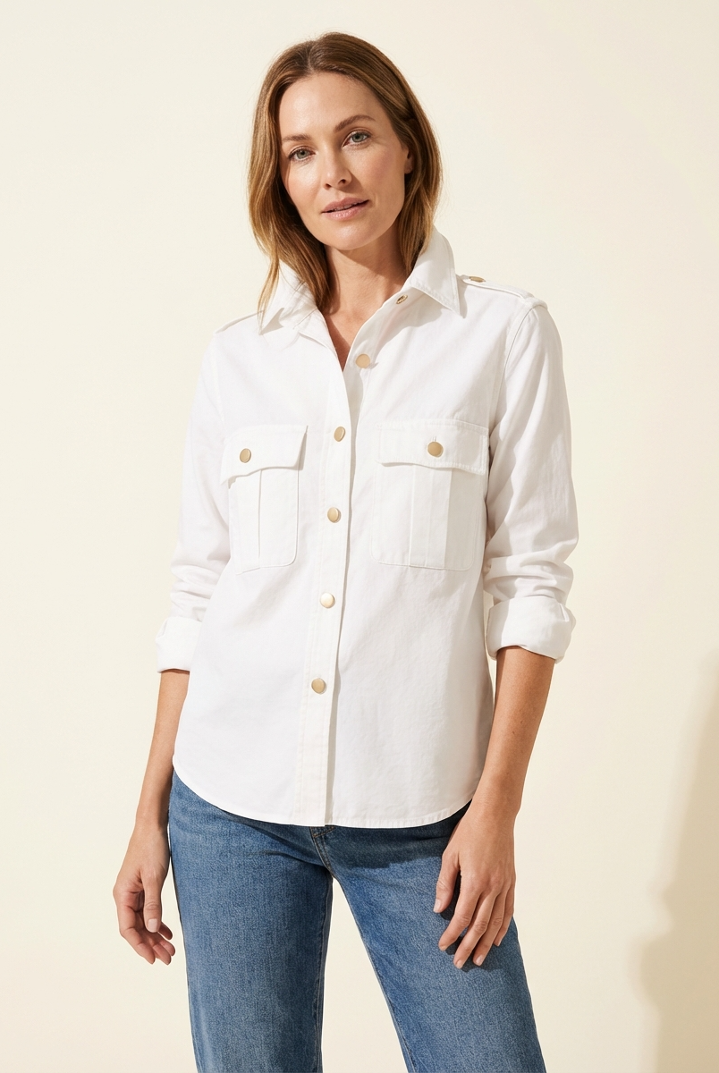 Woman wearing a white shirt with rolled-up sleeves and blue jeans on a beige background