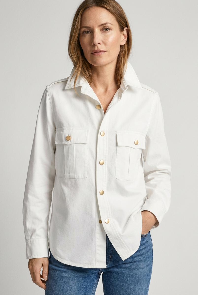 Woman wearing a white shirt with gold buttons on a gray background