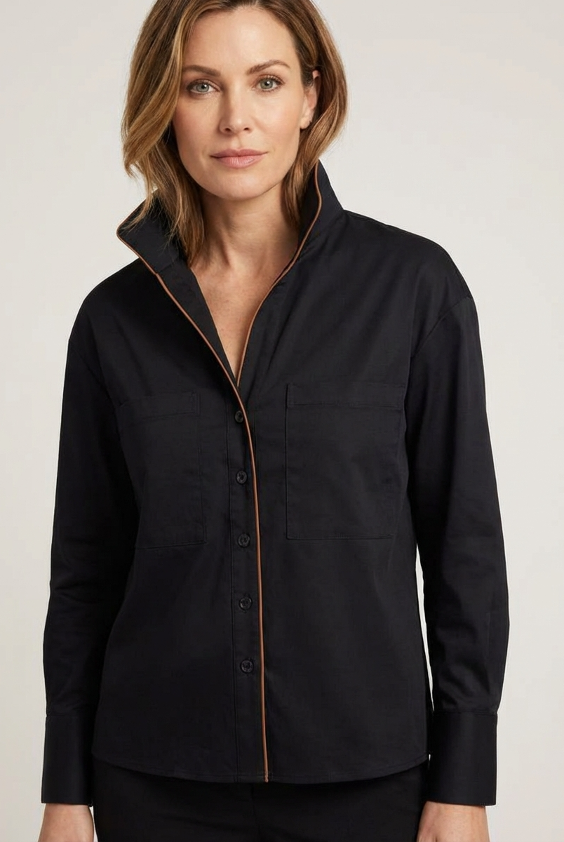 Woman wearing a black shirt with a pipping detail on a plain background