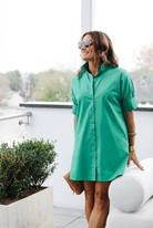 Woman wearing a green dress standing outdoors with blurred background