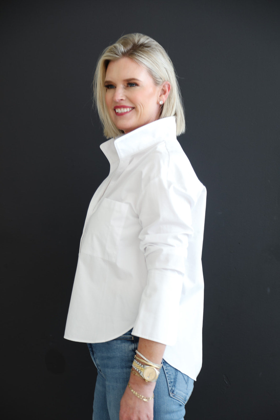 Woman wearing a white shirt and blue jeans against a black background