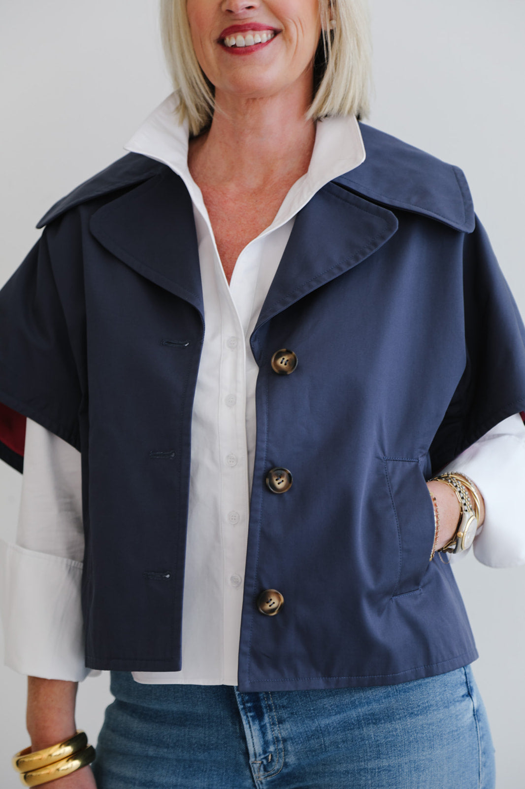 Woman wearing a navy jacket over a white shirt with a plain background