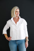 Woman wearing a white shirt and blue jeans against a black background