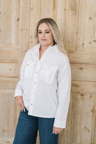 Women's white safari style button up shirt with gold buttons.