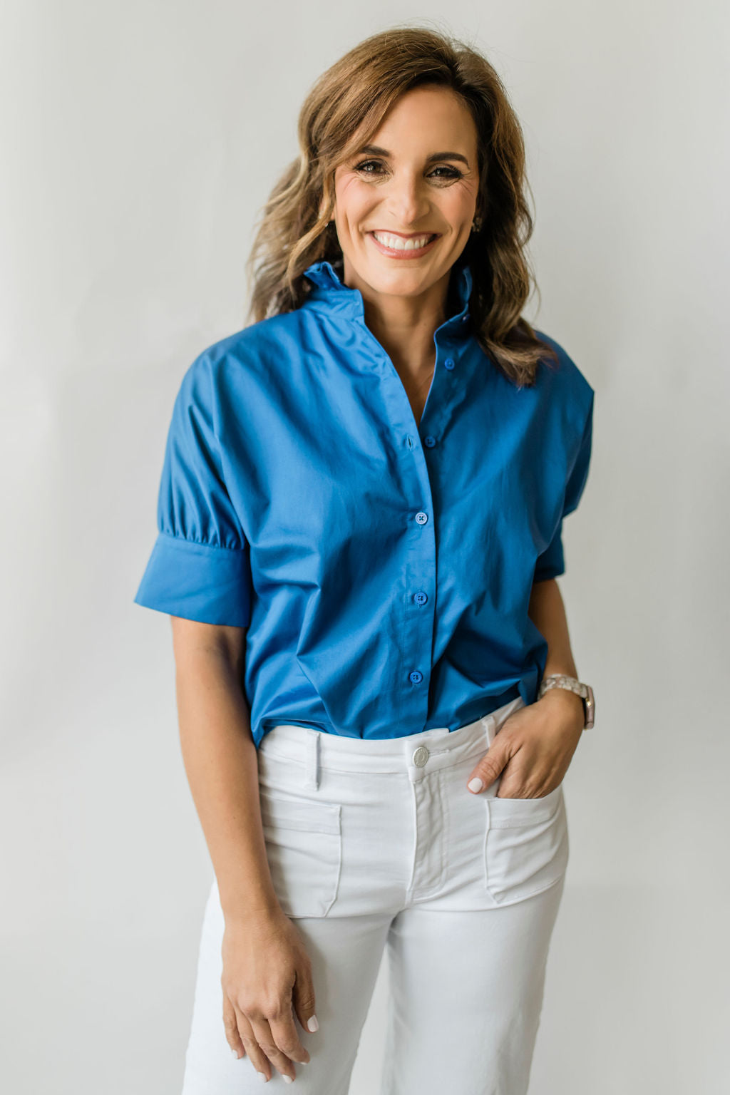 Crisp women's short sleeve button down shirt with a ruffle collar in bright blue.