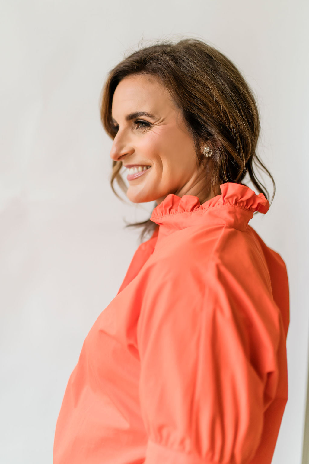 Bright orange women's short sleeve button down shirt with a ruffle collar.