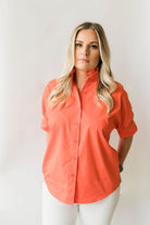 Bright orange women's short sleeve button down shirt with a ruffle collar.