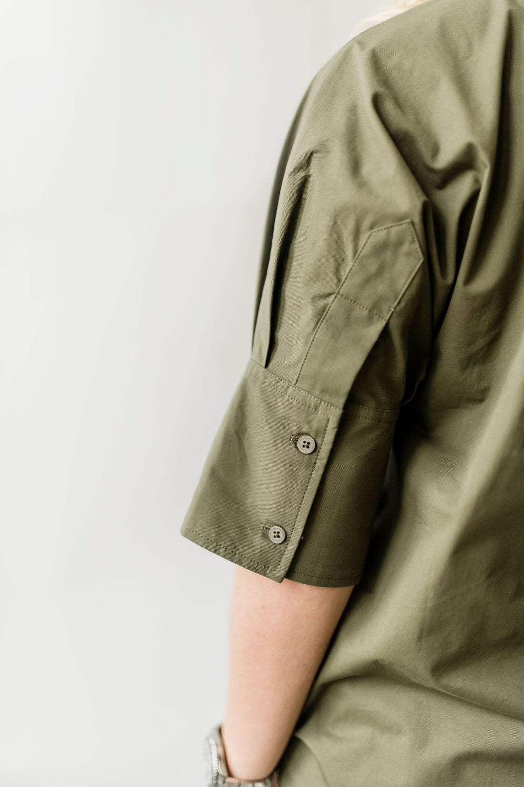 Pullover style short sleeve women's shirt with a short collar and buttons on the sleeves in olive green.