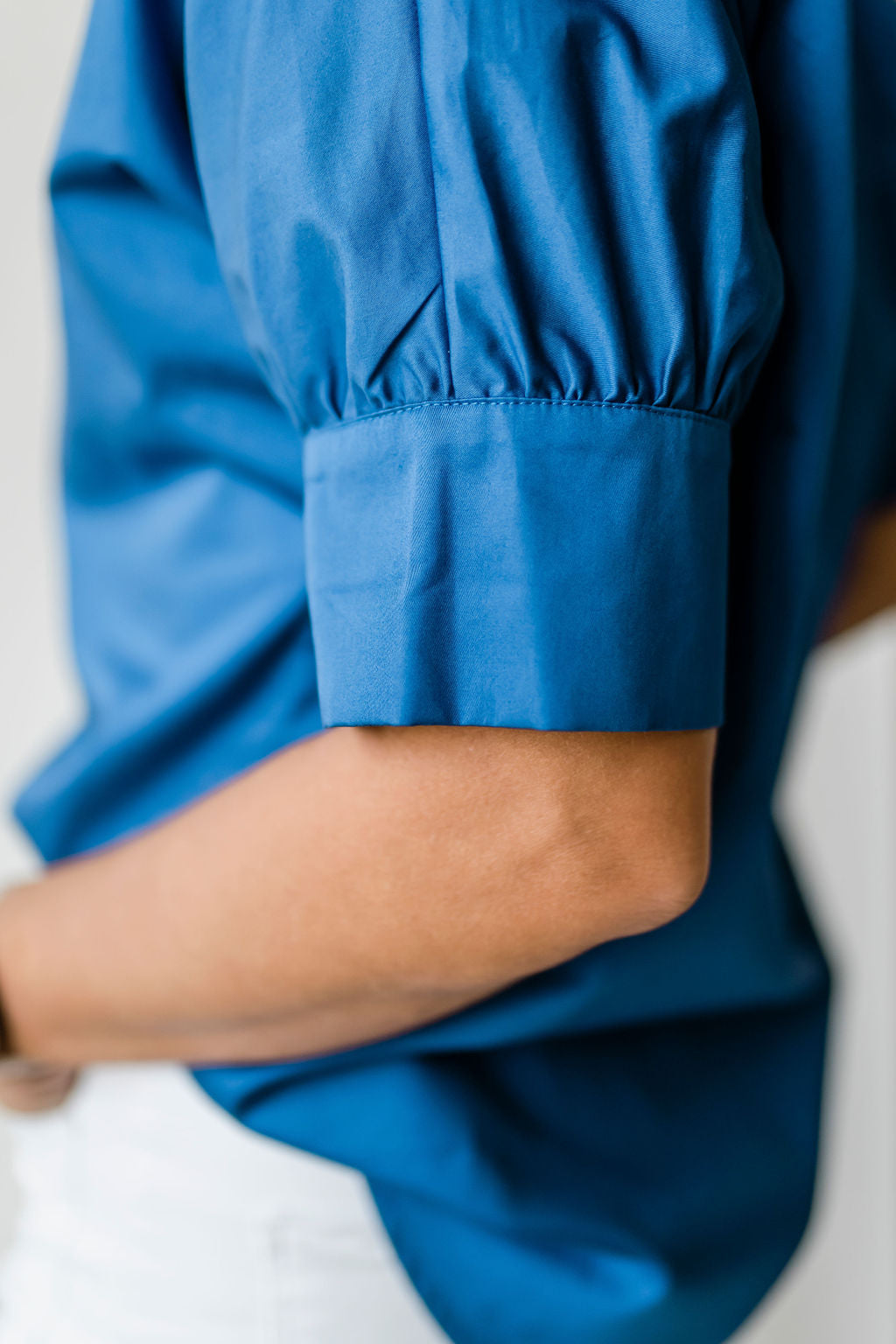 Crisp women's short sleeve button down shirt with a ruffle collar in bright blue.