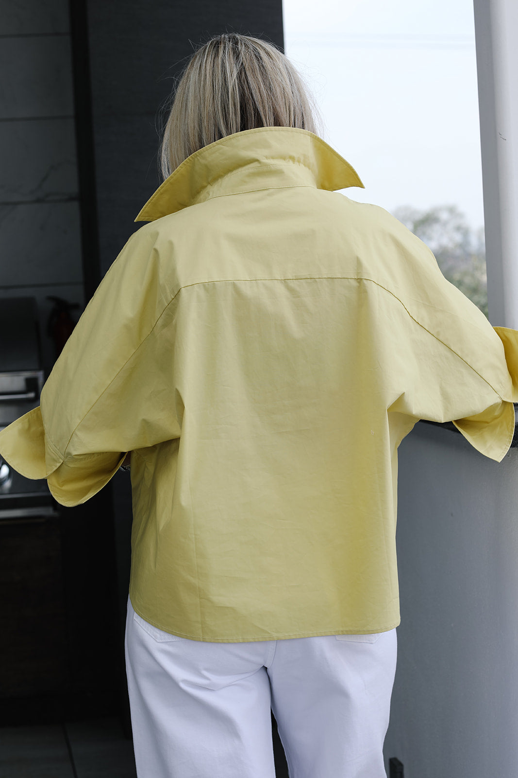Person wearing a yellow shirt standing on a balcony.