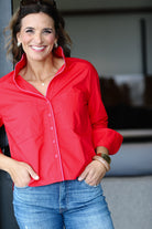 Woman wearing a red shirt and blue jeans with a blurred background