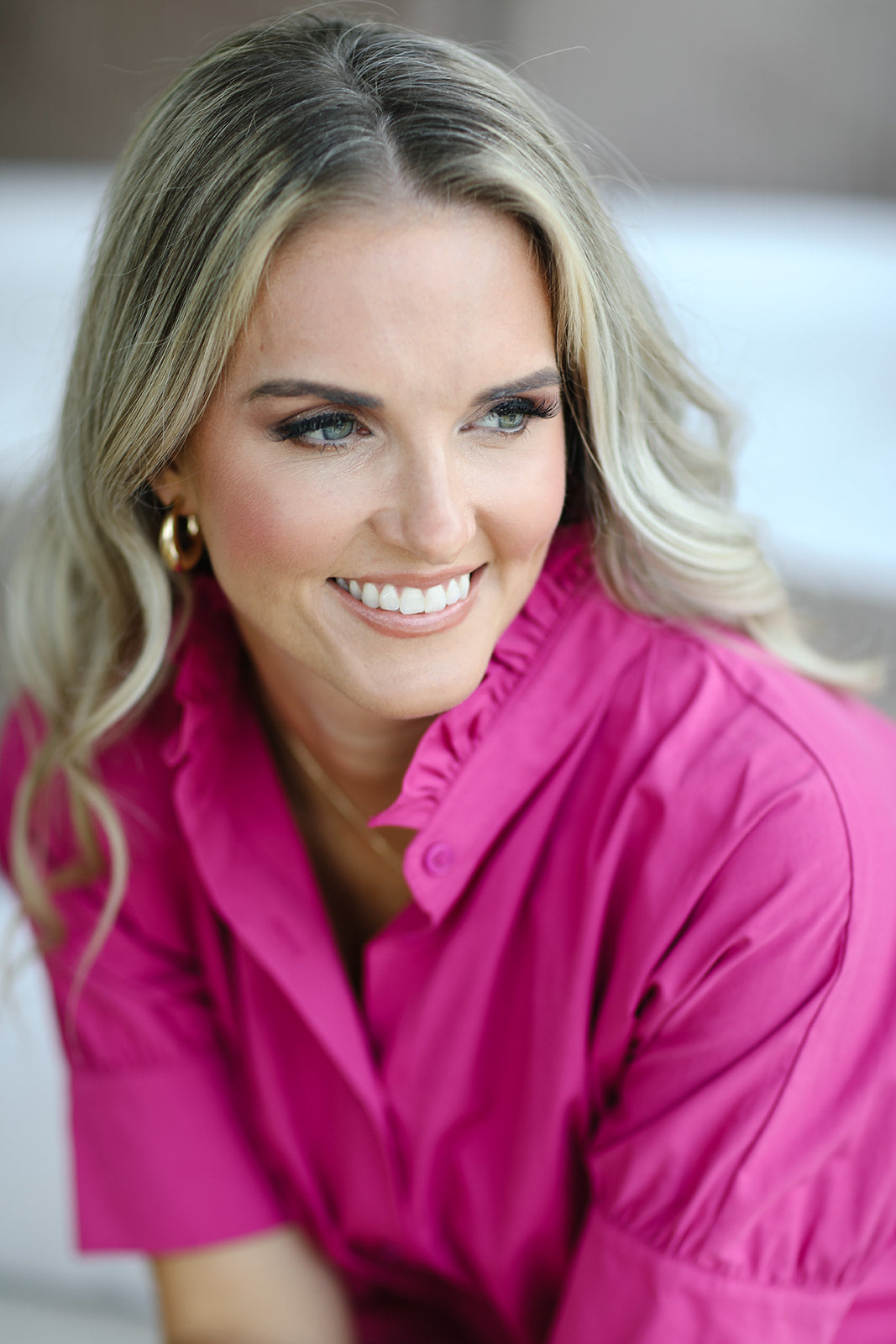 Woman wearing a bright pink shirt with a blurred background