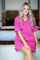 Woman in a pink dress sitting on a bed in a bedroom setting