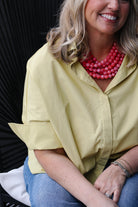 Woman wearing a yellow shirt and pink necklace with a blurred background