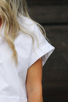 White blouse with ruffled sleeves worn by a person with blonde hair.