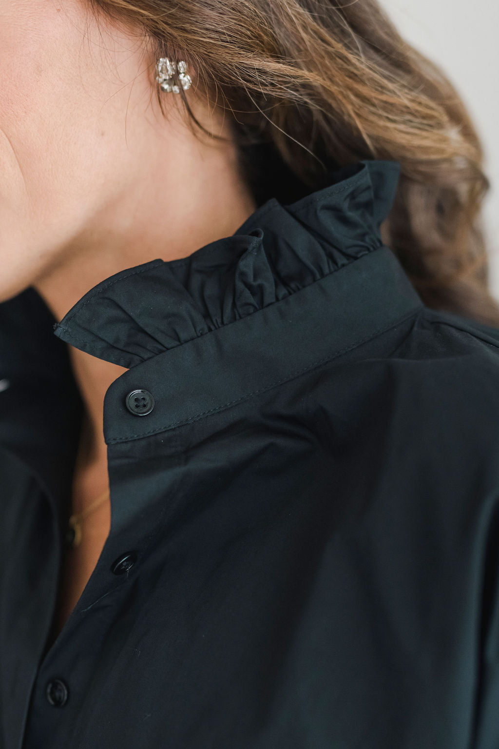 Crisp black button down shirt with a popped ruffle collar and short sleeves.