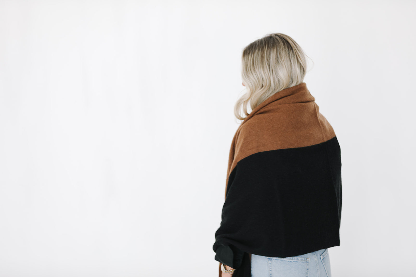 Person wearing a two-tone brown and black shawl on a white background