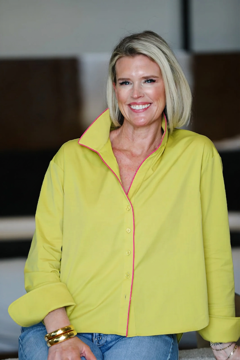 Woman wearing a bright yellow shirt with pink trim in an indoor setting